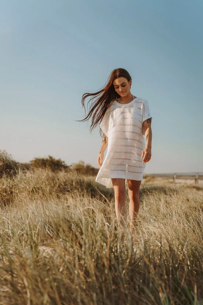 Gold Coast model walking across grassy sand dunes for Gold Coast photographer